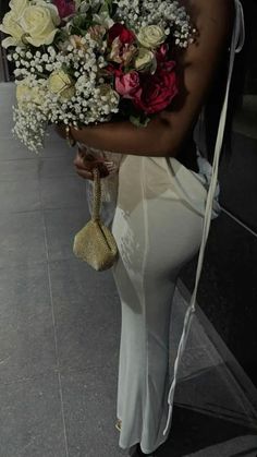 a woman is holding a bunch of flowers in her hand while walking down the street