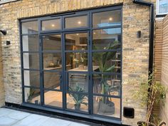 an outside view of a brick building with glass doors and potted plants in the window