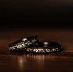 two wedding bands sitting on top of a wooden table