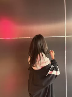 a woman standing in front of a metallic wall with her hands on her hips and looking at the ceiling