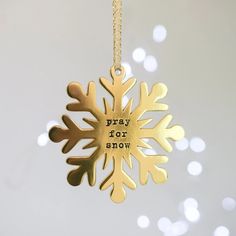 a gold snowflake ornament with the words pray for snow written on it