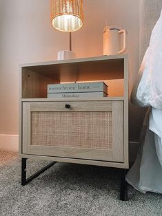 a nightstand with books and a lamp next to it on the floor in a bedroom