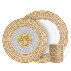 an orange and white dinnerware set with gold trimmings on the rim, in front of a white background