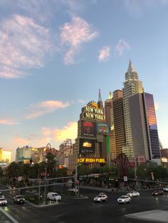 a city street filled with lots of tall buildings under a blue sky covered in clouds