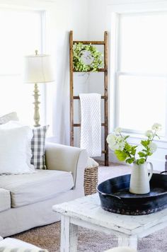 a living room filled with white furniture and flowers in a vase on top of a coffee table