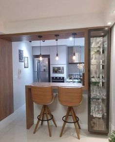 two wooden stools sit at the bar in this modern style kitchen area with white tile flooring