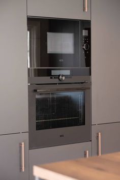 an oven built into the side of a wall in a kitchen with stainless steel cabinets