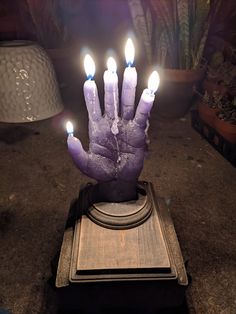 a hand that has been placed on top of a stand with some candles in it