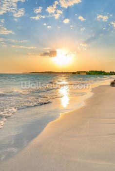 the sun is setting over the water at the beach with waves coming in to shore