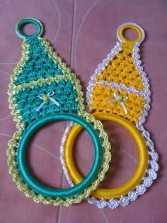 three crocheted christmas tree ornaments are sitting on a table top, one is green and the other is yellow