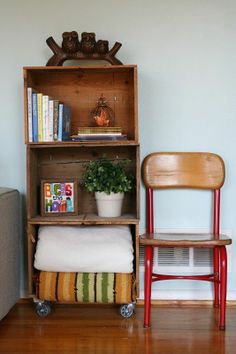 a wooden book shelf sitting on top of a hard wood floor next to a red chair