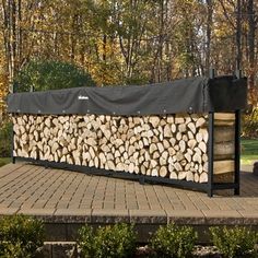 a large pile of logs sitting on top of a brick floor next to trees in the background