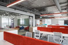 an office with red and white chairs, desks, and glass partitions on the walls