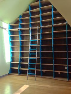 an empty room with shelves and ladders on the wall, in front of a window