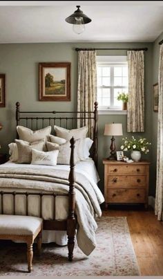 a bedroom with green walls and white bedding, wooden dressers and two windows