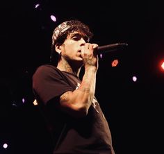 a man holding a microphone in his right hand and wearing a bandana on top of his head