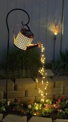 a lit up teapot on top of a stake with fairy lights in the background