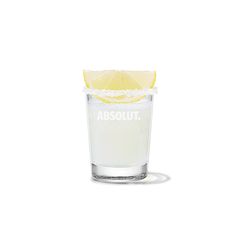 a shot glass filled with white liquid and a slice of lemon on the rim that says absolut