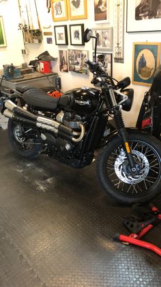 a black motorcycle parked in a garage next to a wall with pictures hanging on it