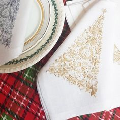 a table topped with plates and napkins on top of a red plaid table cloth