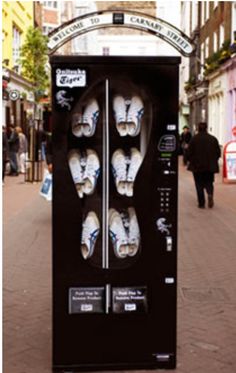 there is a vending machine on the side of the street with shoes in it