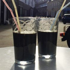 two glasses filled with liquid sitting on top of a table next to eachother