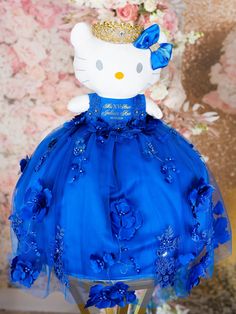 a hello kitty doll wearing a blue dress with flowers and a crown on it's head