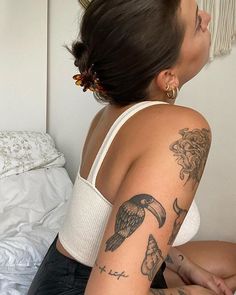 a woman with tattoos on her arm sitting on a bed