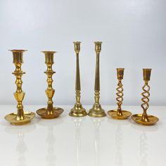 a group of gold candlesticks sitting on top of a white table next to each other