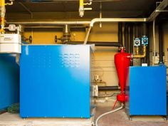 two large blue and red tanks in a room with yellow piping hoses on the wall