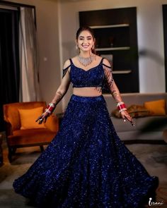 a woman in a blue lehenga and crop top dancing with her arms outstretched