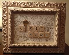 an ornate frame with scrabble letters and a key to the word first home