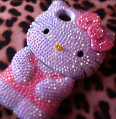 a hello kitty cell phone case is shown on a leopard print surface with pink and purple sequins