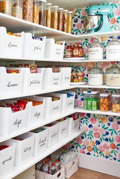 an organized pantry with white bins and floral wallpaper