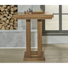 a wooden table with chess pieces on it in front of a pile of wood logs