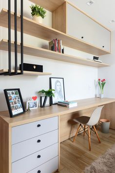 a desk with some books and pictures on top of it, next to a chair