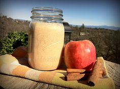 an apple and cinnamon sitting on top of a wooden table next to a mason jar