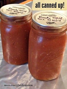 two jars filled with red sauce sitting on top of a white cloth covered tablecloth