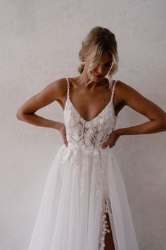 a woman wearing a white wedding dress with sheer tulle and lace on the skirt