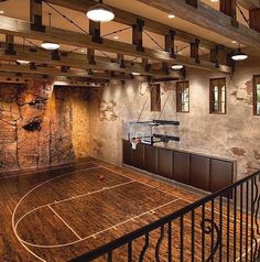 an indoor basketball court in the middle of a room with wooden floors and exposed ceilings