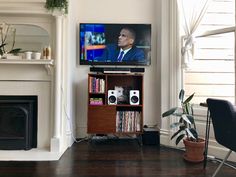 a flat screen tv sitting on top of a wooden shelf in front of a fireplace