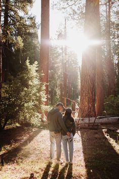 two people standing in the middle of a forest