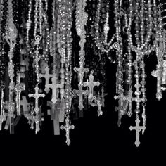 many beads are hanging from the ceiling in this black and white photo with crosses on them