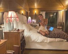 a woman sitting on top of a bed with a laptop computer in her hand while talking on the phone