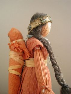 an orange doll with braids on her head and two other dolls in the background