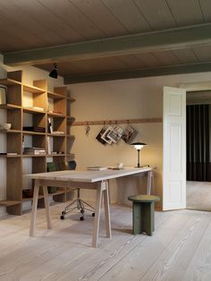 a room with a desk, bookshelf and lamp on the floor in front of it