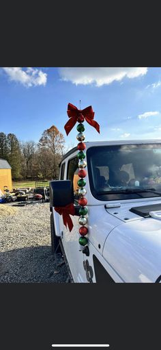 a white truck with red and green decorations on the front door is parked in gravel