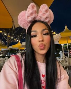 a woman with long black hair wearing pink bunny ears on her head and making a funny face