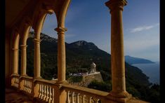 a balcony overlooking the ocean and mountains with columns on each side, looking out to sea