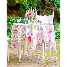 a table with flowers and candles on it in the middle of a patio area next to some chairs